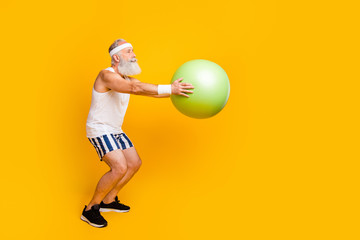 Full length profile photo of aged guy hold green fit ball doing squats serious fat burning...