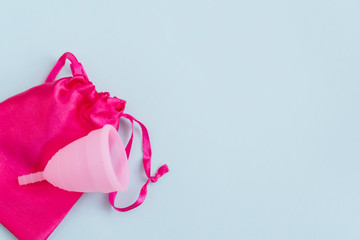 pink menstrual Cup and bag on blue background. woman period concept.