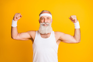 Photo of cheerful positive handsome man smiling toothily showing his muscles demonstrating strength...
