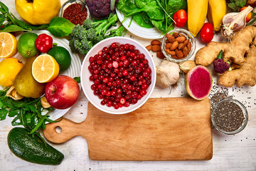 Selection food of rich in antioxidants and vitamins and mineral sources, on white wooden background around cutting board. Healthy balanced dieting concept, ingredients for cooking. Top view, flat lay