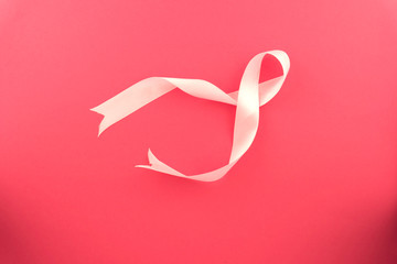 Curled pink ribbon with highlights isolated on pink background, top view. Natural concept.