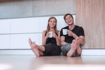 young couple sitting on the floor in new kitchen.