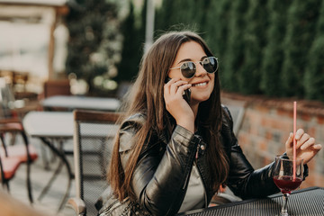 Beautiful woman sitting in a cafe, drinking cocktail and using smartphone. Student during break in the cafe. Lifestyle, technology