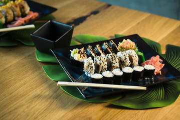 Eating roll sushi in japanese restaurant, hand with chopsticks closeup.. California Sushi roll set with salmon, vegetables.