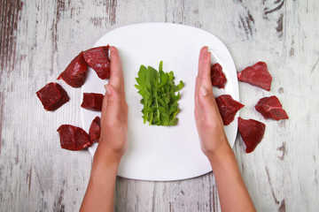 Refusal of meat. Vegetarian's hands reject pieces of red meat.