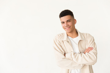 Confident young man smiling at camera. Portrait of handsome happy young man standing with crossed arms and looking at camera. Gesture concept