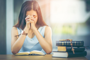 Asian girl with long hair. Read the holy bible and pray for the blessing of Christ. The atmosphere...