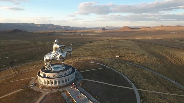 Genghis Khan conjurer Statue Ulaanbaatar Mongolia. Symbol brave nomad man horse ride. Tallest great unique monument museum. Beautiful reflections yellow sunset low sun. Aerial flight