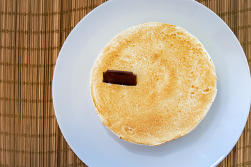On a light tabletop on a straw napkin on a white dish, a classic cheesecake