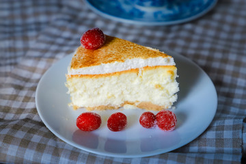 Close-up of a piece of classic cheesecake cake on a white dish and a checkered linen napkin