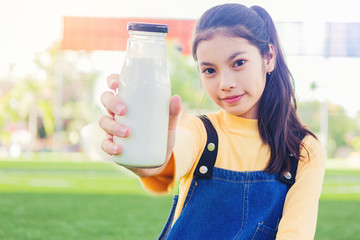 Pretty girl holding and present a bottle of milk.