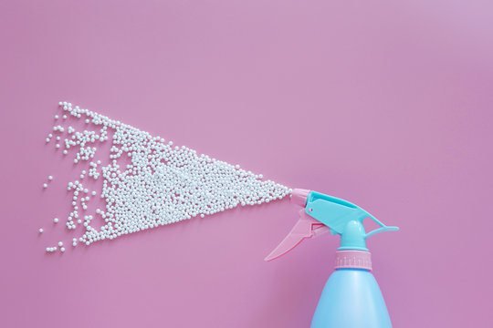 blue spray bottle spraying white bubble foam on pink background with copy space. creative minimal for cleaning concept