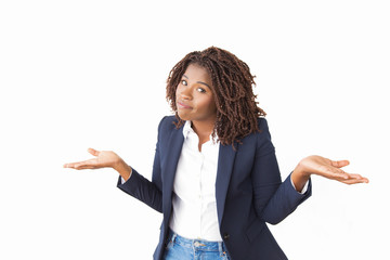 Confused office worker making clueless gesture. Young African American business woman standing...