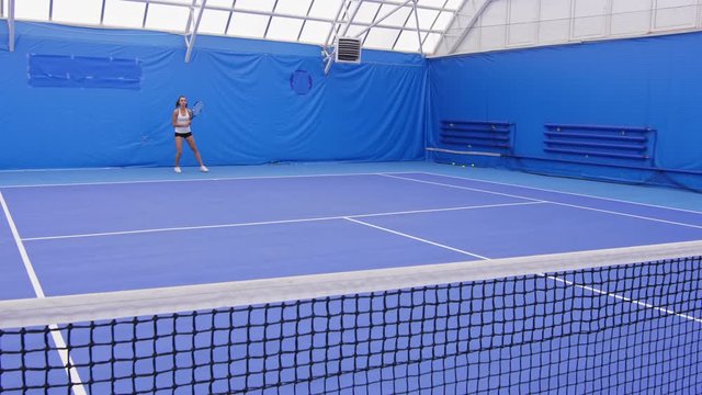 Sportswoman training on tennis court, practicing forehand and backhand