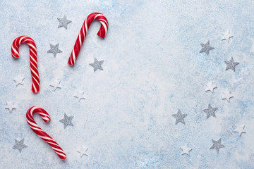 Christmas composition. Frame made of candy canes and stars on blue background. Flat lay, top view, copy space