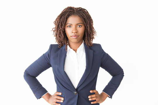 Serious Female Business Leader Posing With Hands On Hips. Young African American Business Woman Standing Isolated Over White Background, Looking At Camera. Confident Businesswoman Concept