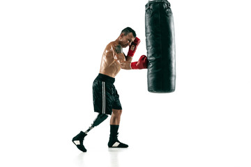 Full length portrait of muscular sportsman with prosthetic leg, copy space. Male boxer in red gloves training and practicing. Isolated on white studio background. Concept of sport, healthy lifestyle.