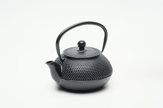 Black cast iron teapot on a white background.
