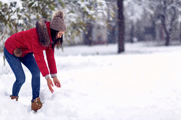 Girl playing with snow. Beautiful young woman in winter.  Happy woman holds snowball in hands.