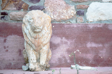 Carved lion statue on the roadside. Patterned wall behind.