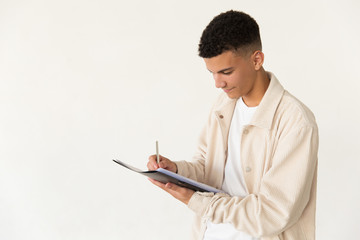 Smiling man writing on papers. Portrait of handsome happy young man holding folder with papers and writing with pen. Taking notes concept