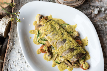Roasted Whitefish with Sauteed Vegetables and Mustard Sauce on White Plate