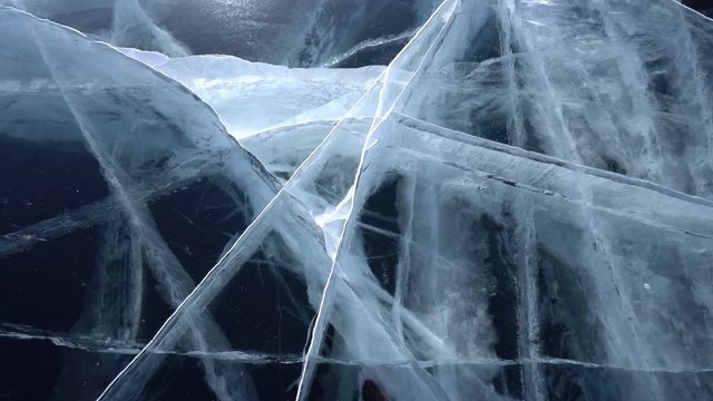 Blue clear transparent fresh pristine ice details. Cinematic deep triangle crack unique pattern. Lake Baikal Russia. North Arctic River Sea. Winter frosty cold. From the ground close-up