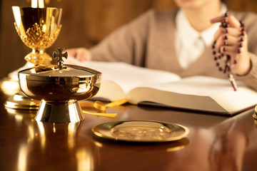 Christian woman with Bible praying in church by the altar. Woman kneeling in prayer with hands...