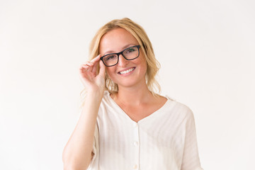 Happy joyful young woman adjusting her glasses. Beautiful woman in casual posing isolated over white background, touching eyewear. Vision concept
