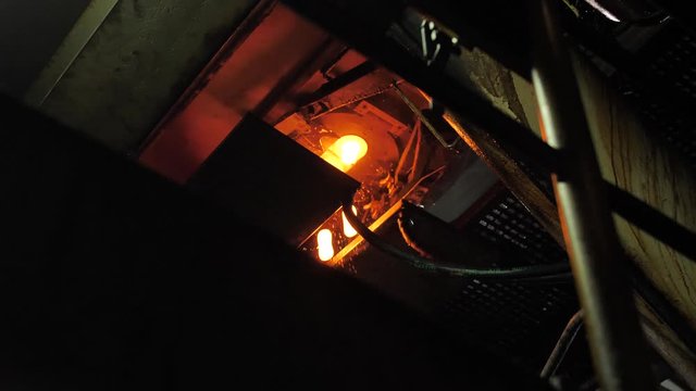 Burning blanks of glass bottles in an industrial stove in Glassworks
