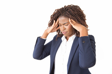 Stressed unhappy businesswoman suffering from headache. Young black business woman with pain face and closed eyes standing over studio background, holding head and temples. Migraine concept