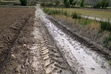 Traces de pneus dans la boue d'un chemin de terre.