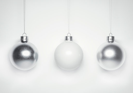 Exciting Glossy metallic christmas baubles hanging in front of white background.