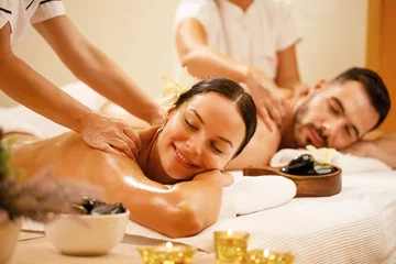 Fotobehang Happy couple enjoying a day at spa while having back massage. © Drazen