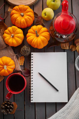 Planning to do list. Autumn mood composition on a wooden table with pumpkins, rowan and leaves. Open notepad with pen and black coffee in the red cup and on grey wooden background, warming drink