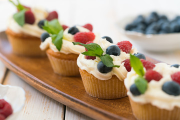 Delicious cupcakes with berries and fresh mint on wooden table