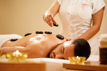 Relaxed man having lastone therapy at health spa.