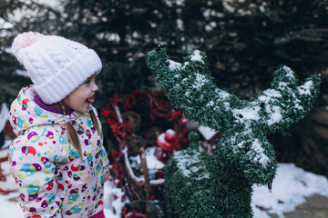 Little cute pretty girl in winter snowy park playing outdoors. Happines, joy, childhood, winetr, chistmas concept