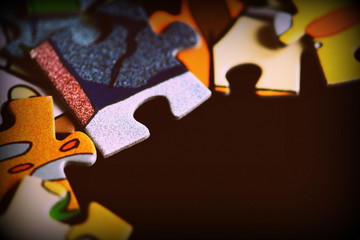 Puzzle pieces scattered on a dark background close up. Retro style toned