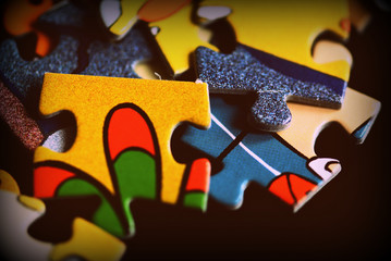 Puzzle pieces scattered on a dark background close up. Retro style toned
