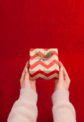 Woman holding Christmas presents on a Red table background..