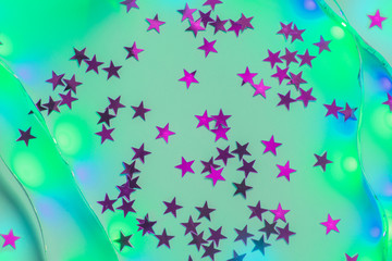 Purple star confetti on mint background with green and purple neon led lights - Christmas festive backdrop