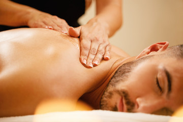 Obraz na płótnie Canvas Close-up of man having back massage with honey at health spa.