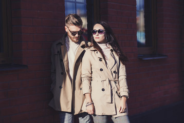 stylish couple in coat and glasses posing in the city