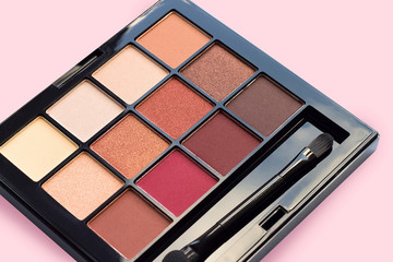 Palette of eyeshadows in brown tones, matte and shimmer eyeshadows on a pink background, close up....