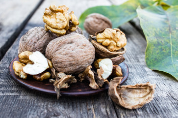 Fototapeta na wymiar Walnuts and walnut kernels lie on a bowl on a rustic old wooden table. Walnut kernels.