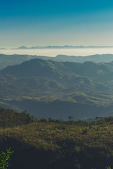 GREEN GRASS ON FOREGROUND AND THE MOUNTAIN STAND ON THE MIDDLE AND THE CLOUDS BEYOND THE MOUNTAIN
