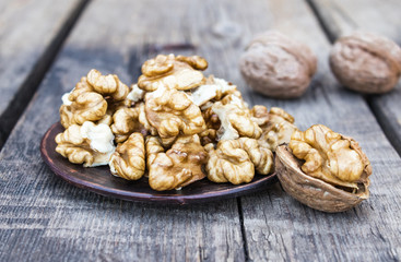 Walnut kernels lie in a bowl on a rustic old wooden table. Fresh walnuts.