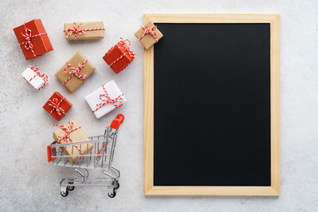 Gift boxes flying out of a shopping cart and empty chalkboard.