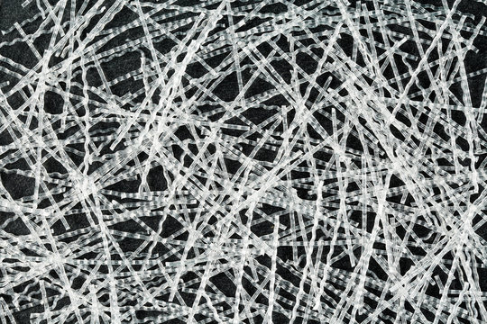 Close up, top down view of sinusoidal polypropylene fibers for concrete structural reinforcement on black stone surface. Construction industry background texture